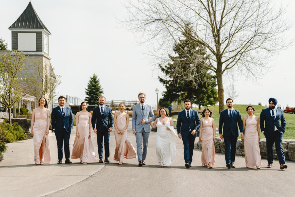 A wedding couple and their bridal party walking in the grounds of whistle bear in cambridge, ontario