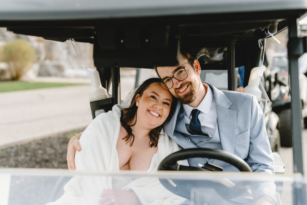 A bride and groom in a golf cart at whistle bear