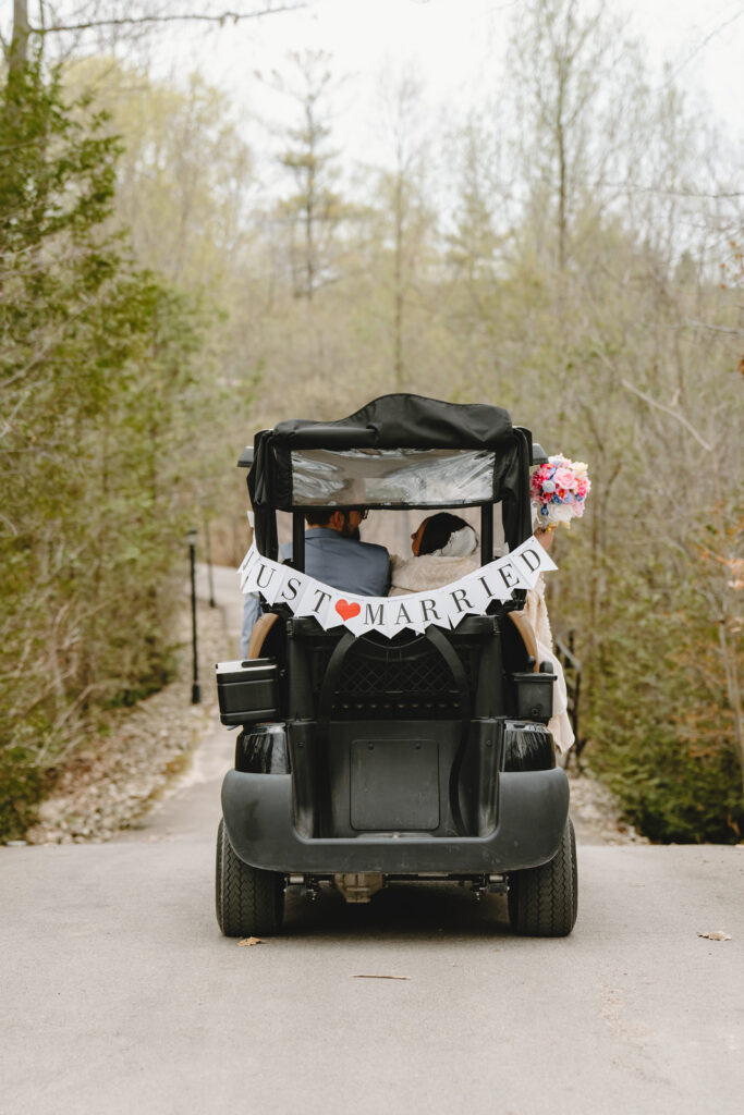 a golf cart driving away with a just married sign at whistle bear