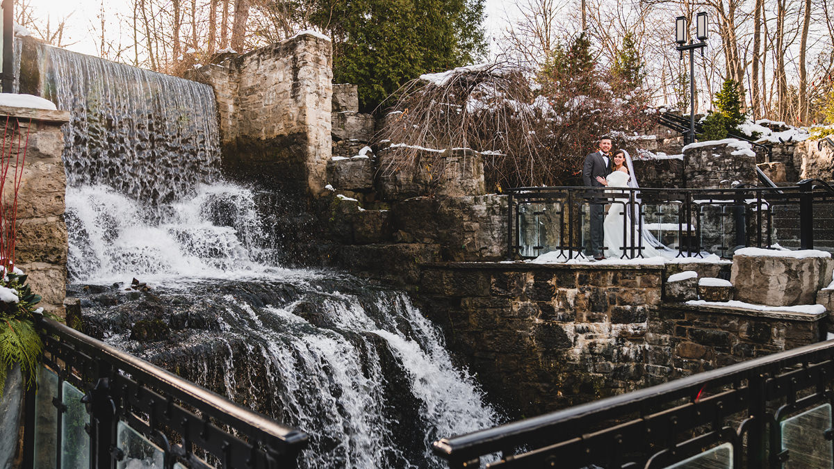 A couple photographed by the waterfall at Ancaster Mill in Winter