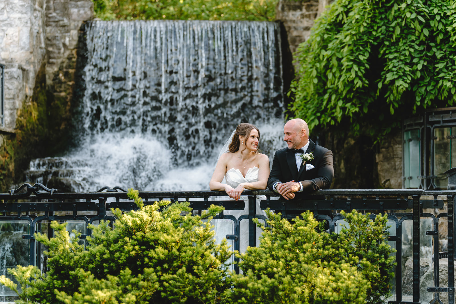 A bride and groom in front of the waterfall at Ancaster Mill