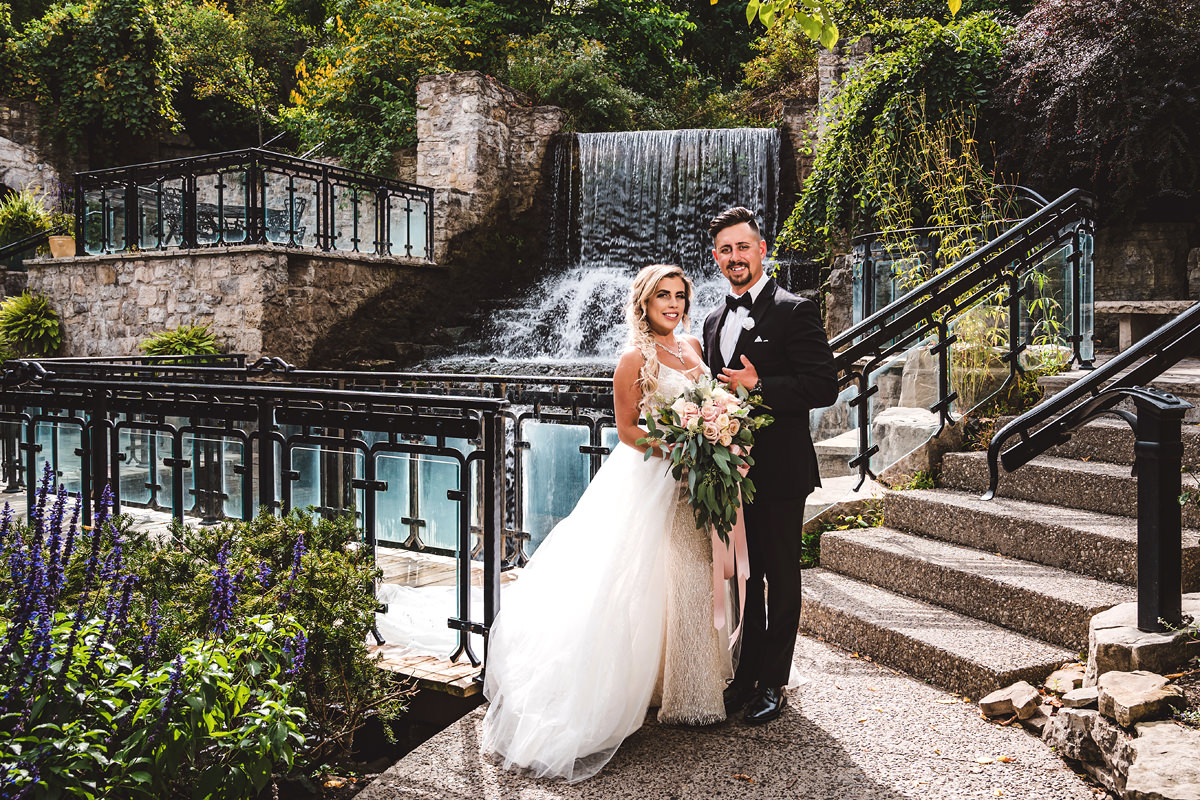 Newlyweds in front of the waterfall at Ancaster Mill