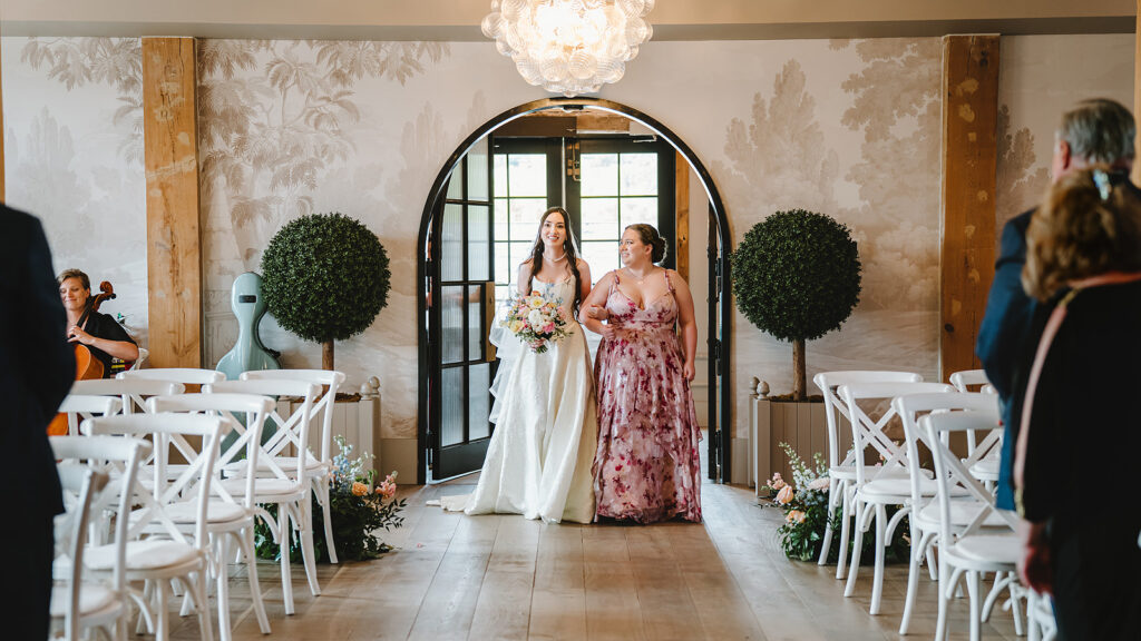 A bride and her sister walking down the aisle at Elora Mill
