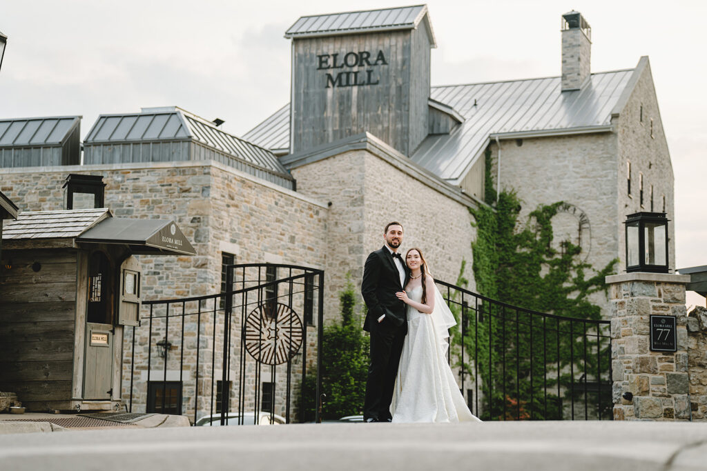 Newlyweds posing in from of Elora Mill, Elora, Ontario