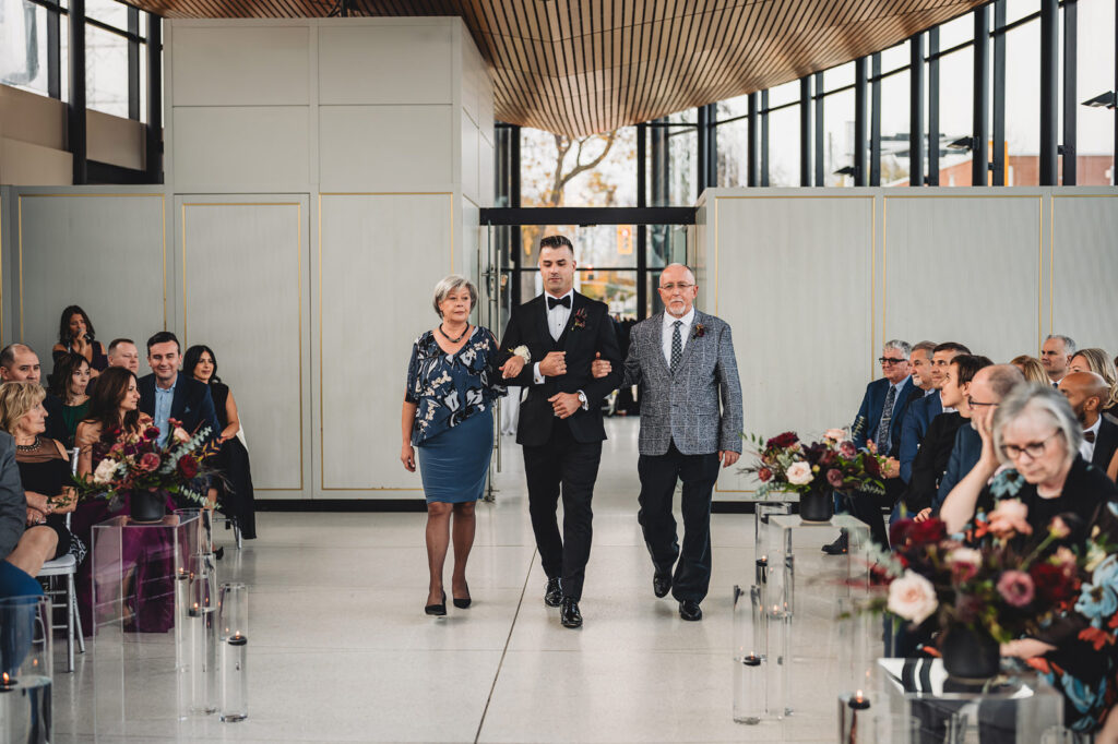 A groom and his parents walking down the aisle at Spencer's at the Waterfront