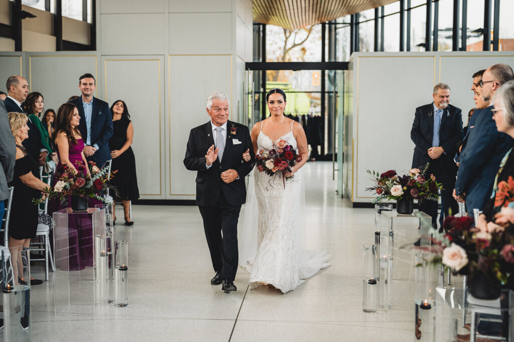 A bride walking down the aisle with her father at Spencer's at the Waterfront