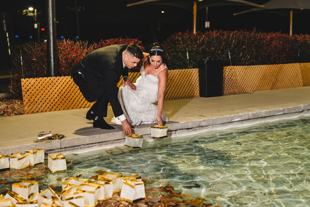 Newlyweds placing floating candles in the water at Spencer's at the Waterfront